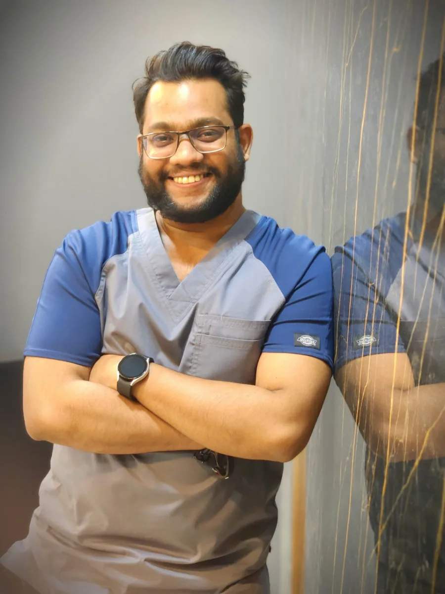 Dr. Ali Rashid smiling in scrubs at his dental clinic
